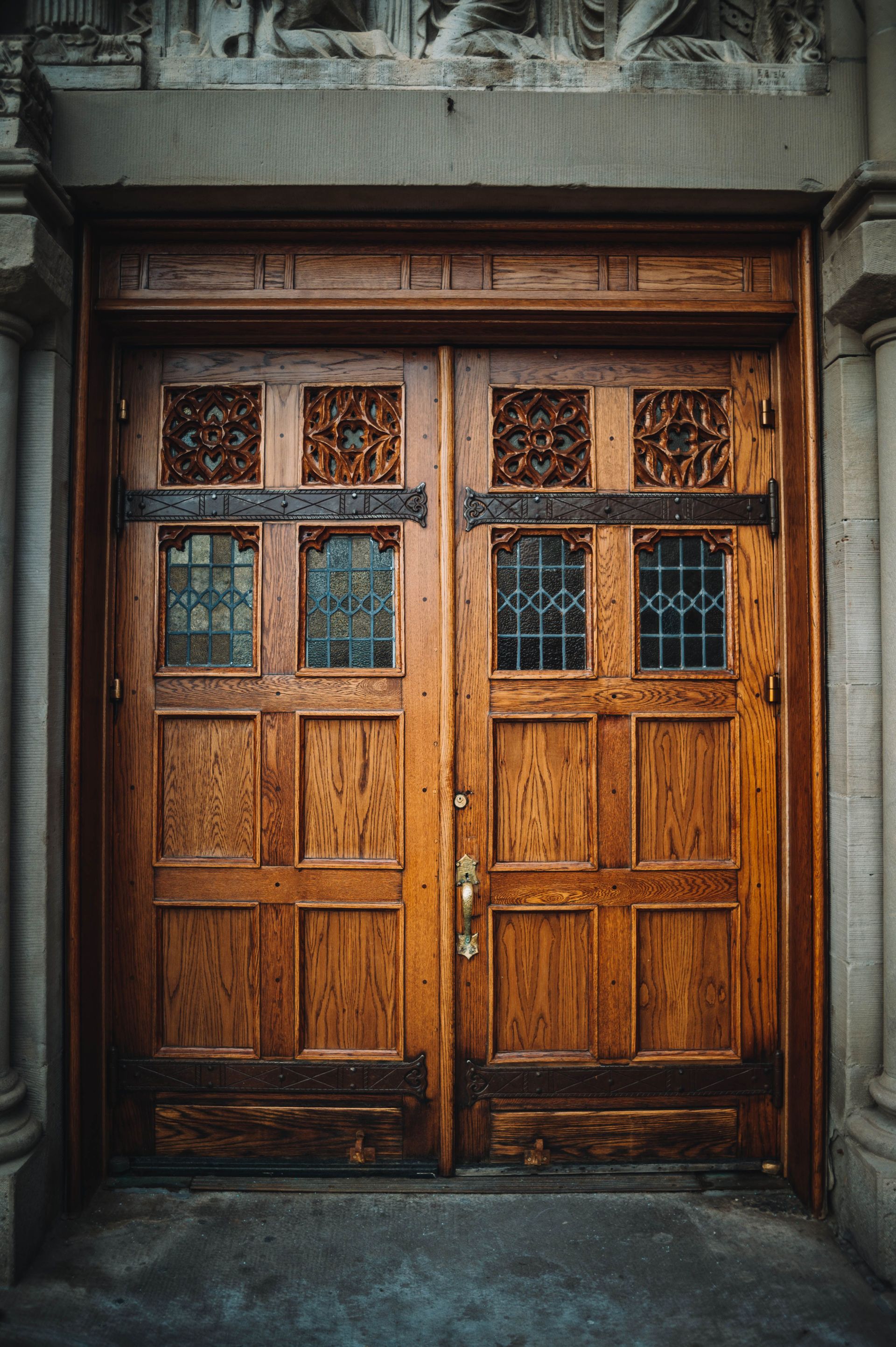 Beautifully crafted vintage wooden church doors with intricate carvings and stained glass.