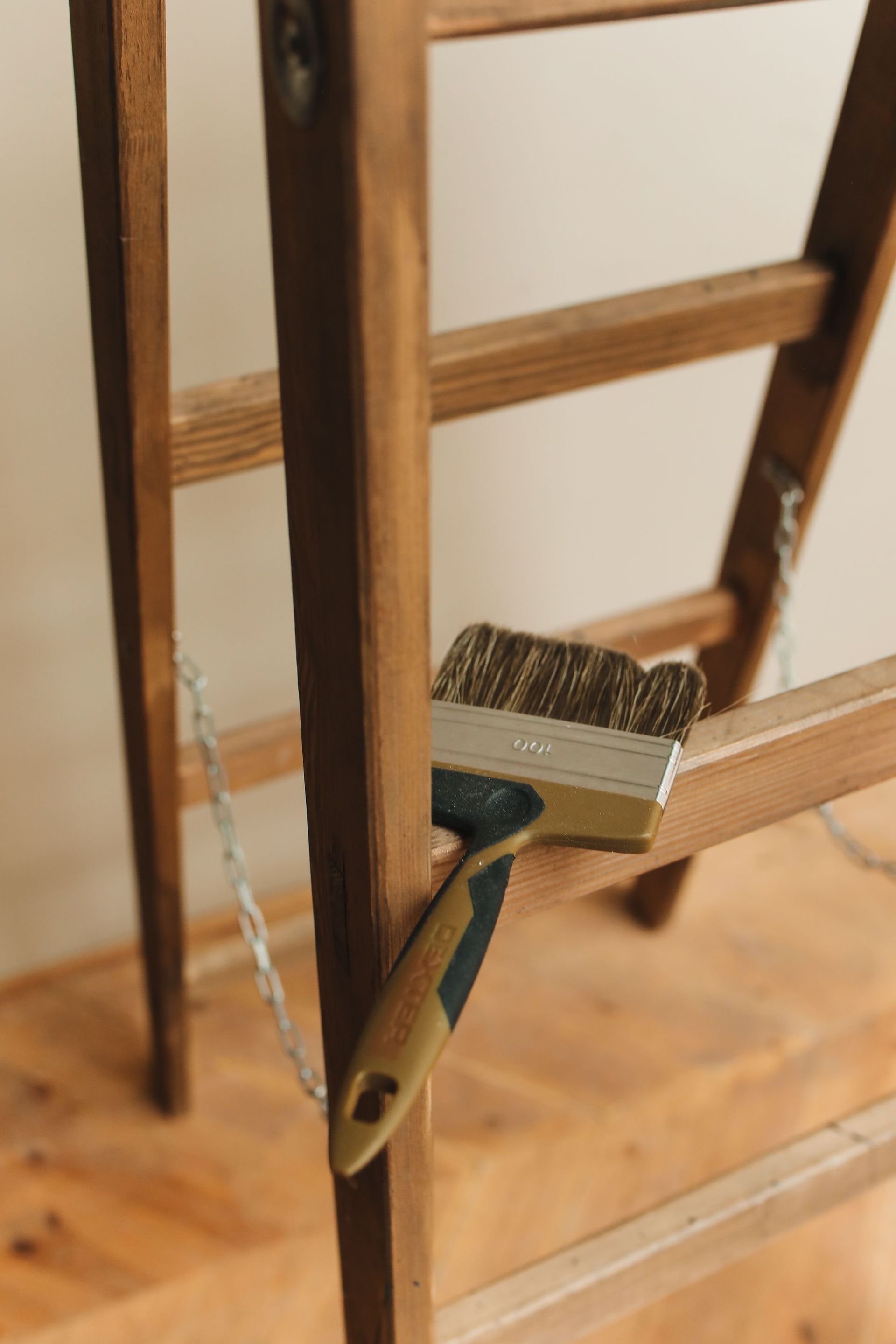 Close-up of a wooden ladder holding a paintbrush, ideal for carpentry and painting themes.